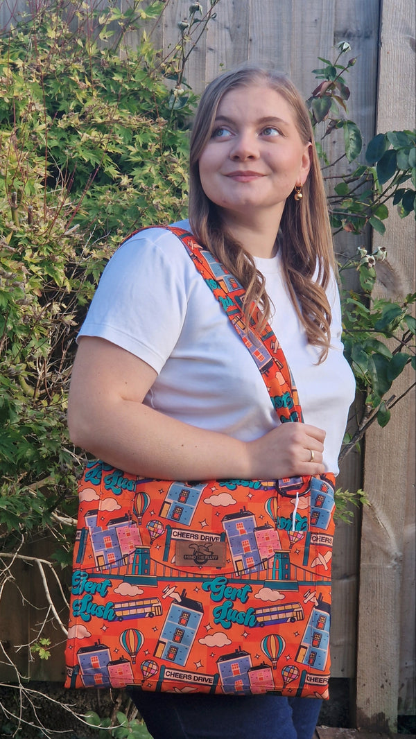 Woman carrying an orange Cheers Drive Bag-to-Mat over her shoulder outdoors